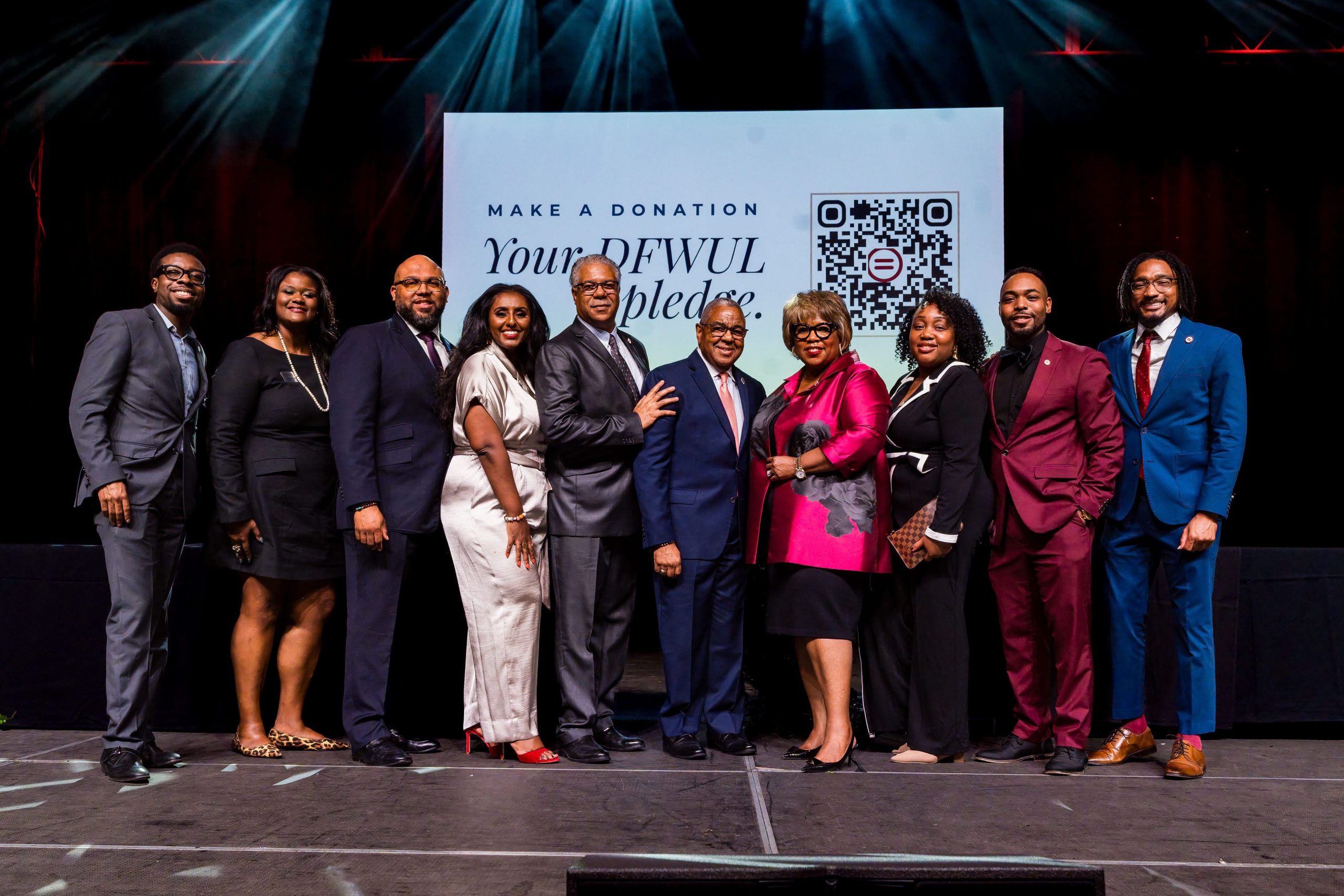 Dallas-Fort Worth Urban League event participants gather onstage in front of a donation screen.
